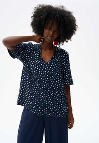 Marineblauwe stippen top van lichtgewicht stof, met een V-hals en korte mouwen. Loose fit met een ronde zoom voor comfort.