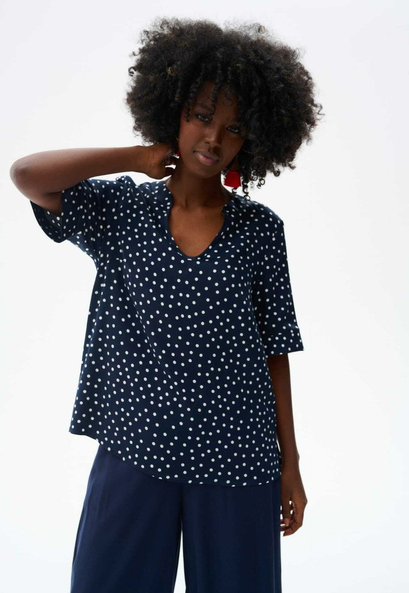 Marineblauwe stippen top van lichtgewicht stof, met een V-hals en korte mouwen. Loose fit met een ronde zoom voor comfort.