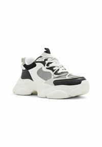 Sneaker chunky con tomaia in mesh e pelle, caratterizzate da blocchi di colore bianco e nero, dettagli testurizzati e una spessa suola bianca.