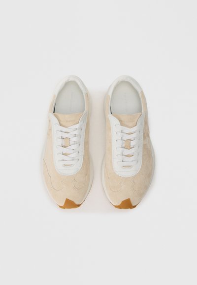 Adidași din suede bej cu șireturi albe, vârful rotund și talpă din cauciuc maro. Au o limbă din piele netedă și detalii cu logo embosat.