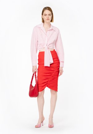 Camicetta bianca tagliata con righe rosse, legata in vita; gonna rossa arricciata; sandali con tacco rosa; borsa rossa con tracolla.