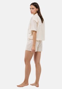 Ensemble de loungewear en coton beige clair, comprenant un haut oversized à manches courtes et un short assorti, avec une coupe décontractée et un simple ourlet.