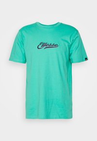 T-shirt en coton turquoise à manches courtes, col rond, avec le logo "Ellesse" brodé en bleu foncé et violet sur la poitrine.
