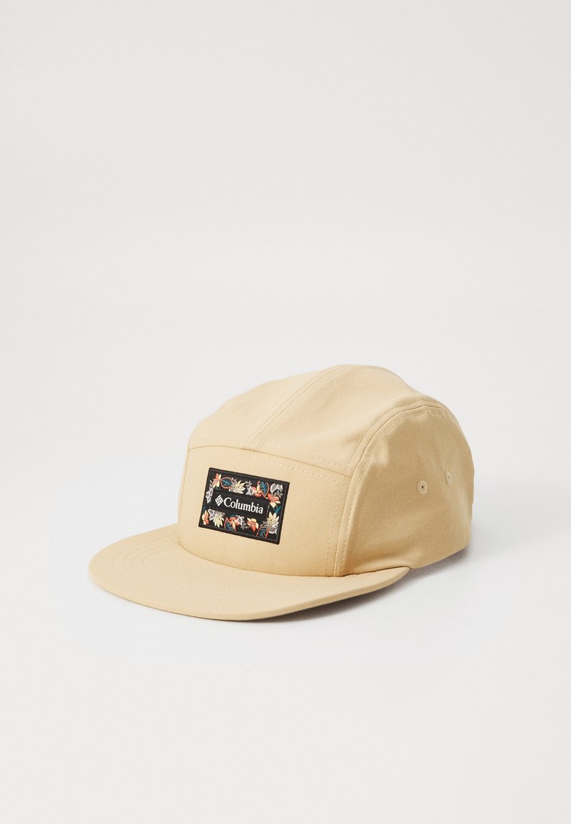 Casquette beige à cinq panneaux avec une visière plate, présentant un patch rectangulaire noir avec une broderie florale colorée et le logo Columbia à l'avant.