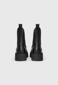 Bottines en cuir noir avec des côtés élastiques, une semelle en caoutchouc épaisse et des languettes à l'arrière. Texture lisse avec un minimum de détails.