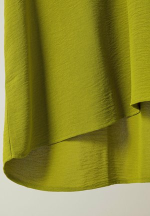 Tejido texturizado de color verde lima con un drapeado fluido. El dobladillo presenta un corte asimétrico sutil, mostrando un material ligero y suave.