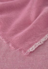 Weiches pinkes Gewebe mit einer strukturierten Webart. Verfügt über ausgefranste Kanten und eine glatte Oberfläche, die seine leichte und luftige Beschaffenheit betont.