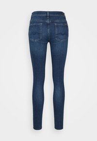 Tmavě modré úzké džíny z denimu s pasem ve střední výšce, dvěma zadními kapsami se šitým vzorem a hladkým, přiléhavým střihem.