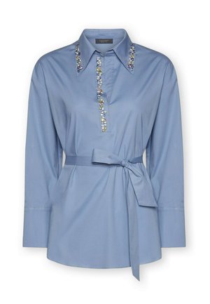 Camicia azzurro chiaro in tessuto con colletto e maniche lunghe. Presenta decorazioni ornamentali lungo la linea del colletto e una vita annodata.