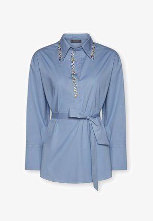 Camisa azul claro de tela con cuello y mangas largas. Presenta adornos decorativos a lo largo del cuello y una cintura atada.