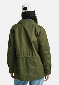 Olivengrüne, leichte Jacke aus strapazierfähigem Material mit lockerer Passform, Knopfmanschetten und einer verstellbaren Taille durch eine Rückenraffung.