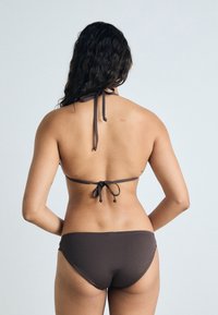 Brown bikini set featuring a halter neck and tie-back design. The bottom has a classic cut, with a smooth texture and minimal stitching.