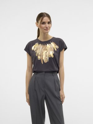 Dark grey short-sleeve t-shirt featuring a gold feather design across the chest; paired with high-waisted, tailored grey trousers.
