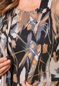 Bedruckte Bluse in Schwarz, Beige und Grau mit abstrakten Pinselstrich-Mustern. Weicher Stoff mit einem runden Halsausschnitt und ohne sichtbare Beschläge.