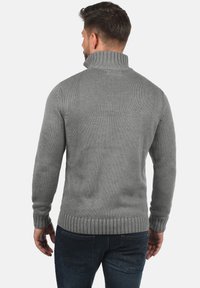 Maglione grigio a maglia con colletto alto, polsini e orlo a coste, tessuto testurizzato e design aderente, che mette in mostra uno stile classico maschile.