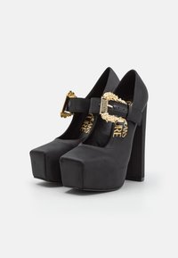 Czarne platformy na wysokim obcasie z satynowym wykończeniem, zaokrąglonym noskiem, wysokim słupkowym obcasem oraz dekoracyjnym złotym zapięciem na pasku.