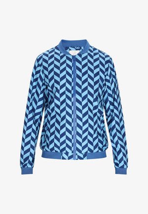 Sininen pommittajatakki, jossa on rohkea viistokuvio eri sävyissä vaaleansinisestä tummansiniseen, vetoketjukiinnityksellä ja ribbaetuilla hihansuilla.