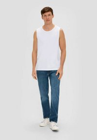 White sleeveless top, blue denim jeans, and white sneakers. The top is simple, while the jeans are straight-fit with a blue wash.