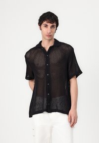 Schwarzes, kurzärmeliges Hemd mit Knopfleiste aus offenem Strickmaterial, mit einem kragenlosen Ausschnitt und einer lockeren, entspannten Passform.