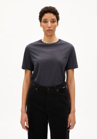 Donkergrijze katoenen t-shirt met korte mouwen en een ronde hals, gecombineerd met hoge zwarte spijkerbroek. Soepele textuur, casual pasvorm.