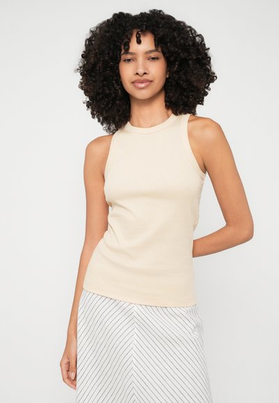 Bež riban top brez rokavov z visokim ovratnikom, v kombinaciji z krilom z navpičnimi črtami. Gladka tekstura.