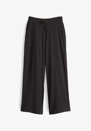 Pantaloni a gamba larga neri, realizzati in tessuto testurizzato. Presentano un elastico in vita con cordoncino e tasche laterali.