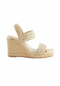 Sandal s klinastom potpeticom s gornjim dijelom od pletene slame u bež boji, s dva široka remena i sjajnom metalnom unutrašnjosti. Teksturna uže ukras na peti.