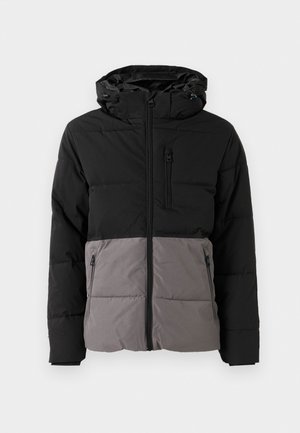 Puffjakke i svart og grå, med glidelås foran, hette, to sidelommer og en brystlomme, med quiltet tekstur.