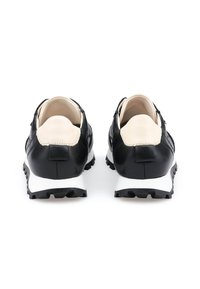 Scarpe in pelle nera con una superficie liscia, suola in gomma bianca e dettagli crema in contrasto sul tallone e sul colletto. Design a profilo basso.