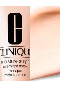 Clinique Moisture Surge Overnight Mask i et rosa rør. Kremaktig tekstur vist ved siden av. Svart tekst på røret beskriver produktnavn og bruk.