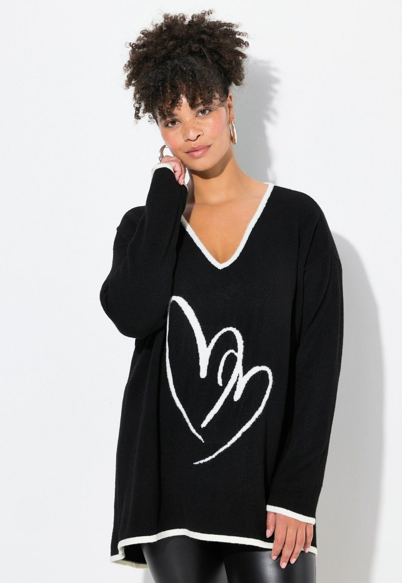Schwarzer übergroßer Pullover mit weißem V-Ausschnitt und Herzdesign. Weicher Stoff, lange Ärmel und abgerundeter Saum.