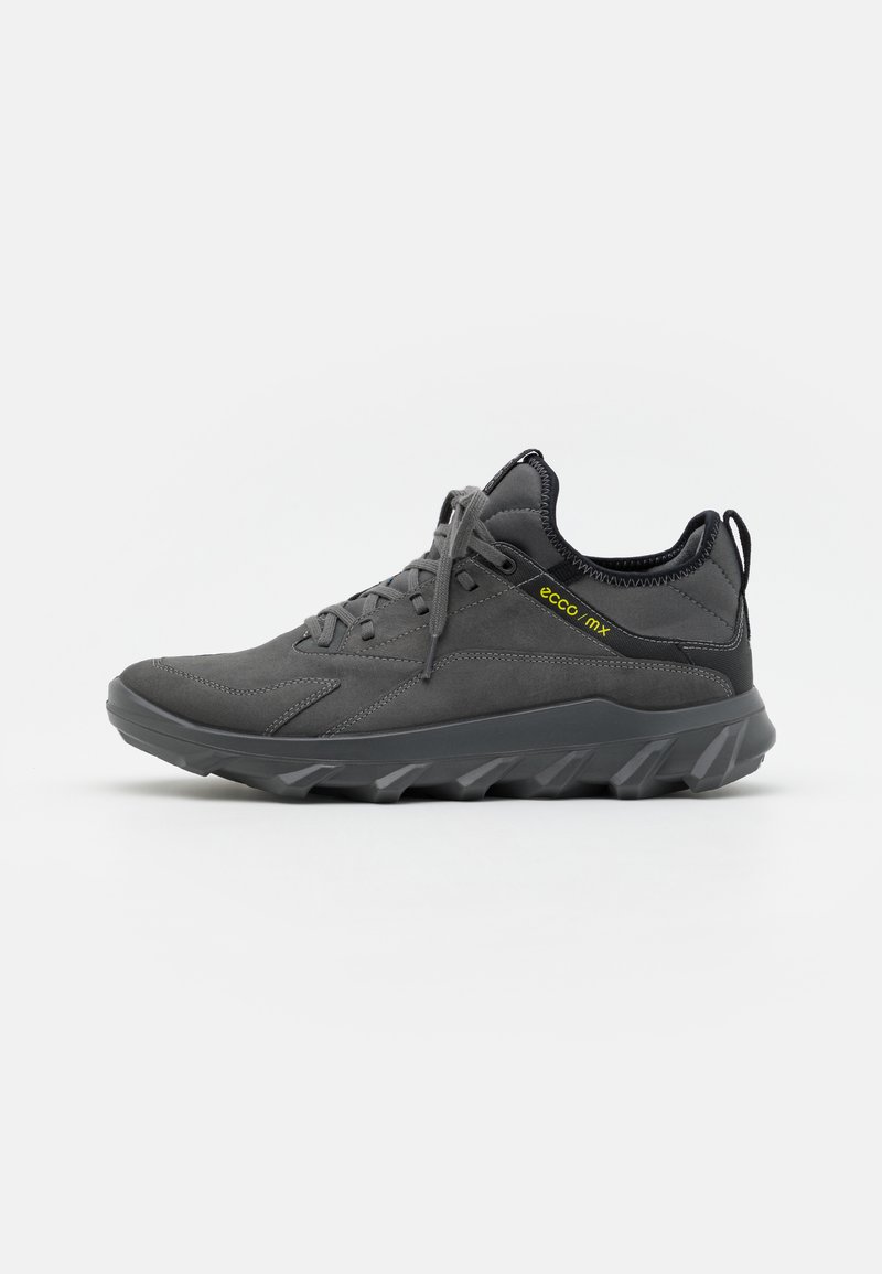 Dark grey athletic shoe featuring a suede and textile upper, textured sole with pronounced treads, and a subtle logo accent.