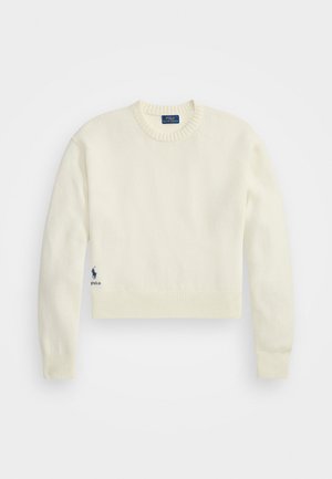 Cream-colored cropped sweater made of soft fabric. Features a ribbed neckline and hem, with a small blue logo on the lower left side.