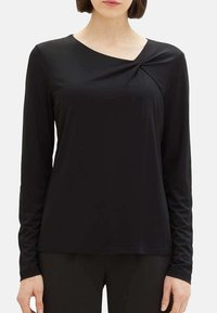 Haut noir à manches longues avec un détail de nœud tordu à l'épaule, fabriqué en tissu lisse et extensible, avec un col rond et un design ajusté.