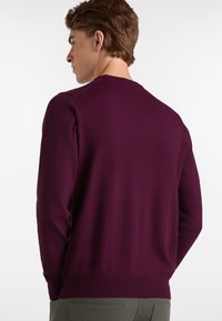Weinroter Pullover mit Rundhalsausschnitt, gerippten Bündchen und Saum sowie einer glatten Textur. Die Rückansicht zeigt ein tailliertes Design mit minimalen Nähten.