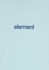 Camiseta de algodón de color azul claro con la palabra "elemento" en letras negritas color navy en el centro, con un cuello redondo y mangas cortas.