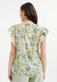 Bloemige blouse van licht, doorschijnend materiaal met een mix van gele en groene patronen. Geruffelde korte mouwen en een ronde halslijn.