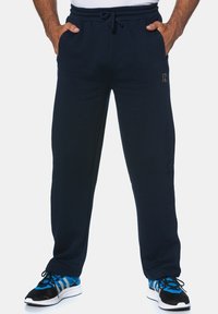Navy blue sweatpants made of soft fabric, featuring an elastic waistband with a drawstring, side pockets, and a logo detail on the leg.