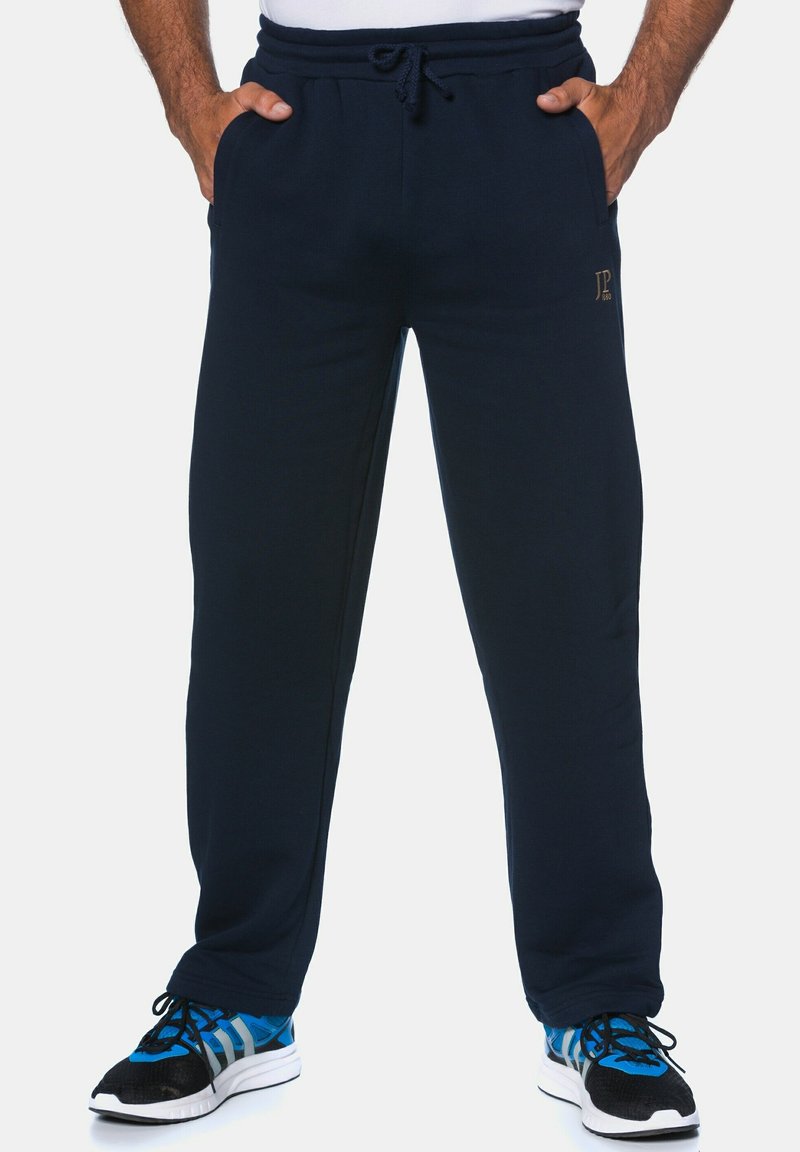 Navy blue sweatpants made of soft fabric, featuring an elastic waistband with a drawstring, side pockets, and a logo detail on the leg.