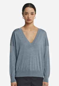 Jasnoniebieski sweter w serek z długimi rękawami i prą�żkowanym wykończeniem. Miękka tekstura, luźny krój i obniżona linia ramion.