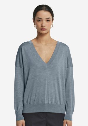 Hellblauer V-Ausschnitt-Pullover mit langen Ärmeln und geripptem Saum. Weiche Textur, lockere Passform und Design mit fallendem Schulterbereich.