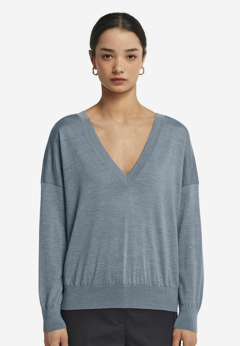 Jasnoniebieski sweter w serek z długimi rękawami i prążkowanym wykończeniem. Miękka tekstura, luźny krój i obniżona linia ramion.