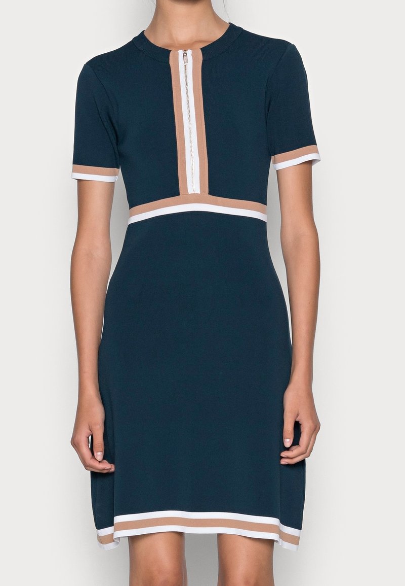 Robe bleu marine à manches courtes avec une patte de boutonnage zippée, ornée de rayures crème et marron clair au col et à l'ourlet. Coupe ajustée, longueur genou.