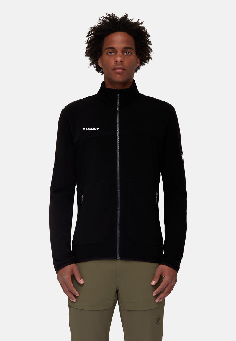 Giacca in pile nera con colletto alto, zip frontale completa e tasche con zip. Presenta un logo sul petto e un tessuto testurizzato.