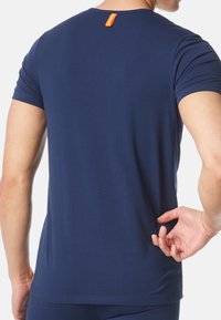 Marinblå T-shirt med korta ärmar i mjukt tyg, rund halsringning och en orange etikett på baksidan. Figursydd design utan mönster.