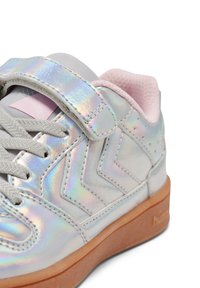 Kinderschuh in silberner, irisierender Optik mit grauen Schnürsenkeln, Klettverschluss, pink gepolstertem Kragen und Sohle aus Gummilaufsohle, aus seitlicher und frontaler Perspektive gezeigt.