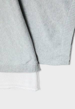 Strati di tessuto lavorato a maglia grigio e bianco con bordi a coste, mostrati su uno sfondo chiaro uniforme.