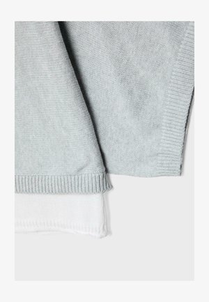 Strati di tessuto lavorato a maglia grigio e bianco con bordi a coste, mostrati su uno sfondo chiaro uniforme.