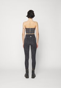 Svart denim strapless topp med en dragkedja i ryggen, parat med höga svarta leggings med ett zebramönster och svarta kängor.