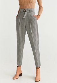 Grijze geruite broek met hoge taille, riemlussen en bijpassende riem. Bevat zijzakken en taps toelopende pijpen, gecombineerd met beige enkellaarsjes.